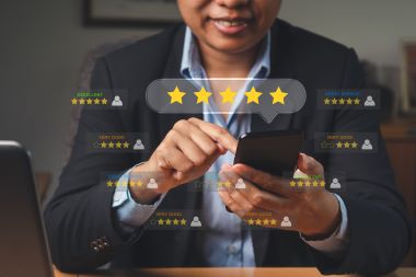 A businesswoman using a smartphone gives the five-star icon a rating of very impressed for service.