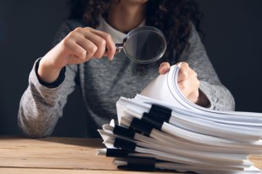 investigation woman holding magnifying glass and documents.